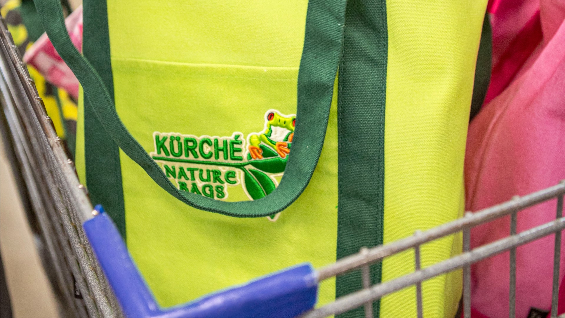 Extreme close-up of a yellow Kurche Nature Bag in a cart, focusing on the nature-inspired logo and high-quality fabric for reusable shopping.