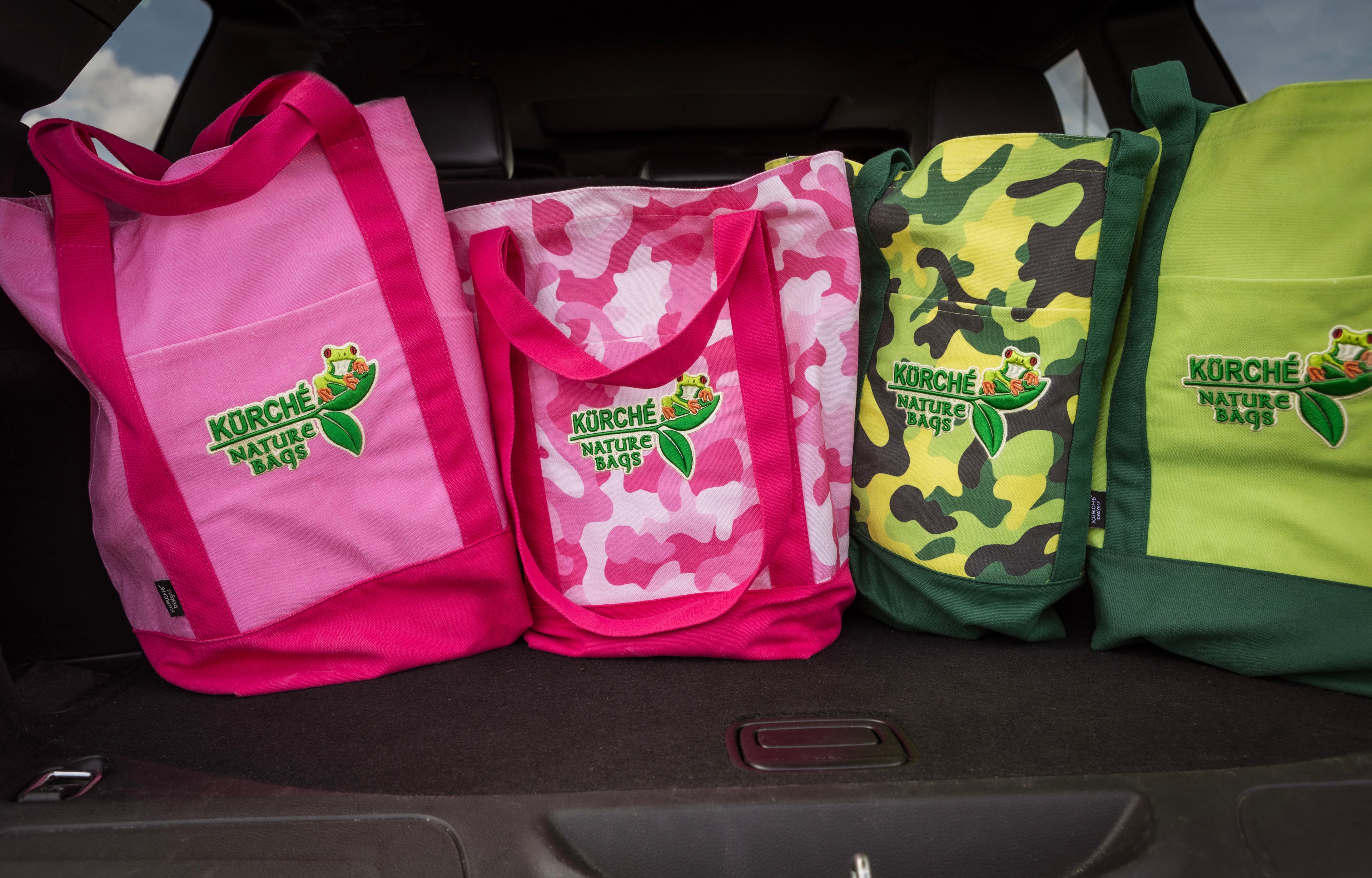 Collection of pink, green, and yellow Kurche Nature Bags in a car trunk, highlighting versatile colors and designs for eco-friendly transport and storage.