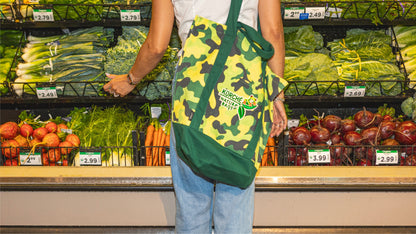 Shopper selecting fresh produce while wearing a yellow camo Kurche Nature Bag, perfect for eco-conscious grocery trips.